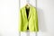 Lime color jacket hanging on white wall. Generate ai