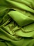 Lime green crumpled fabric bed sheets texture view from above background