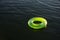 Lime green inflatable ring floating on dark water