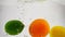 Lime, lemon and orange are dropping in water on isolated background. Video citrus in slow motion.