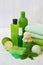 Lime mint composition of beauty threatment products in green colors on a white concrete background: shampoo, soap, bath salt, towe