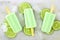 Lime yogurt popsicles with fresh lime slices on white marble