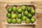 Limes in a wooden box view from above rest on a wooden table with copy space for your text