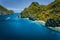 Limestone karst coastline of Matinloc Island with tourist boats in ocean strait. El Nido, Palawan, Philippines. Drone