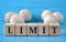 LIMIT - word on wooden cubes on a blue background with wooden round balls