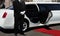 Limo driver standing next to opened car door with red carpet