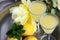 Limoncello in elegant liquor glasses with lemons, mint and yellow rose on steel plate. Sicilian lemon liquor aromatic