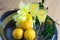 Limoncello in elegant liquor glasses with lemons, mint and yellow rose on steel plate on wooden table. Sicilian liquor