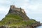 Lindisfarne Holy Island Castle view from coastline with cloudy sky