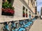 Line of blue public bicycles under window boxes of red flowers in front of the Chicago Cultural Center