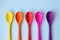 A line of bright multi-colored spoons on a blue background