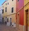 Line of brightly painted traditional houses on a cobbled quiet curved empty street in ciutadella menorca with wooden shutters an