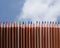 line of colored crayons on a blue sky with clouds