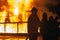 Line of firefighters standing with hose in front of a burning structure during firefighting exercise