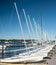 Line of identical small sailboats evenly spaced on dock with no sails