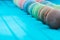 Line of multicolored macaron or macaroons on a turquoise wooden background, almond cookies in pastel tones on a blue