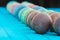 Line of multicolored macaron or macaroons on a turquoise wooden background, almond cookies in pastel tones, selective