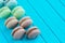 Line of multicolored macaron or macaroons on a turquoise wooden background, almond cookies in pastel tones. Top view