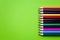 Line multicolored wooden pencils isolated on green background. Colored wooden crayons. Concept of art