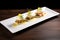 a line of three eggs benedicts on a long rectangular plate, ready to serve