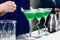 Line of three glasses with green cocktail on bar counter, select