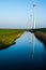 Line of windmills reflecting on a channel of water