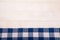 A linen napkin with blue cells lies flat on a white wooden background. Horizontal