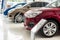 A lineup of new cars on display inside a showroom or dealership. Concept of auto market business in Asia