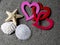 Linked Valentine`s hearts on sand with other beach treasures