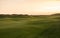 Links golf hole with rolling fairway in evening light