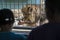 Lion eating in a Zoo cage with visitors watching.