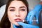 Lip Augmentation. Closeup Of Beautician Doctor Hands Doing Beauty Procedure To Female Lips with Syringe. Young Woman`s