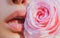 Lips with lipstick closeup. Tenderness pink rose. Lips care. Tenderness womans lips with pink rose. Tenderness woman