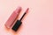 Lipstick and applicator wand on pastel pink backgrpund. Liquid lip stick open tube. Makeup cosmetic product
