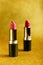 Lipsticks on golden glittery background. Fashionable red lipgloss on shimmering sequin backdrop. Creative luxury cosmetics, makeup