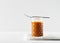 Liquid brown caramel in glass or jar with spoon on white background