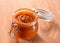 Liquid cream caramel sauce glass jar close-up on wooden background