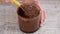 Liquid dark chocolate with nuts in bowl. Female hand mixing melted dark chocolate with spatula.