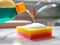 Liquid detergent from the bottle is poured onto the colored sponge
