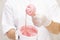 Liquid pink sugar paste or wax for depilation on a wooden stick close up on a white background, against the background of the unif