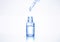 Liquid serum drop from pipette into a cosmetic transparent glass bottle