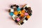 Liquorice Allsorts Sweets in heart shape on pink background. Copy space