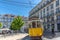 Lisbon, Portugal - May 9th 2018 - Tourist and locals riding a traditional yellow tram in downtown Lisbon, in a beautiful blue sky