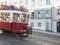 Lisbon, Portugal, October 24, 2021: Close up view of red tourist vintage tram driving down steep narrow Lisbon street of