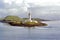 Lismore Lighthouse standing on island with sea foreground cloudy skies in muted colours
