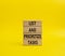 List and prioritize tasks symbol. Concept words List and prioritize tasks on wooden blocks. Beautiful yellow background. Business