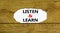 Listen and learn symbol. Words `Listen and learn` on white paper. Beautiful wooden background. Business, educational and listen