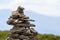 Lit by bright summer sun uneven mountain stones stacked and balanced like pyramid pile on green grassy valley on light white blue