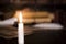 A lit candle against the background of blurred scrolls, books and bird feathers