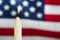 Lit candle with blurred out USA flag in background